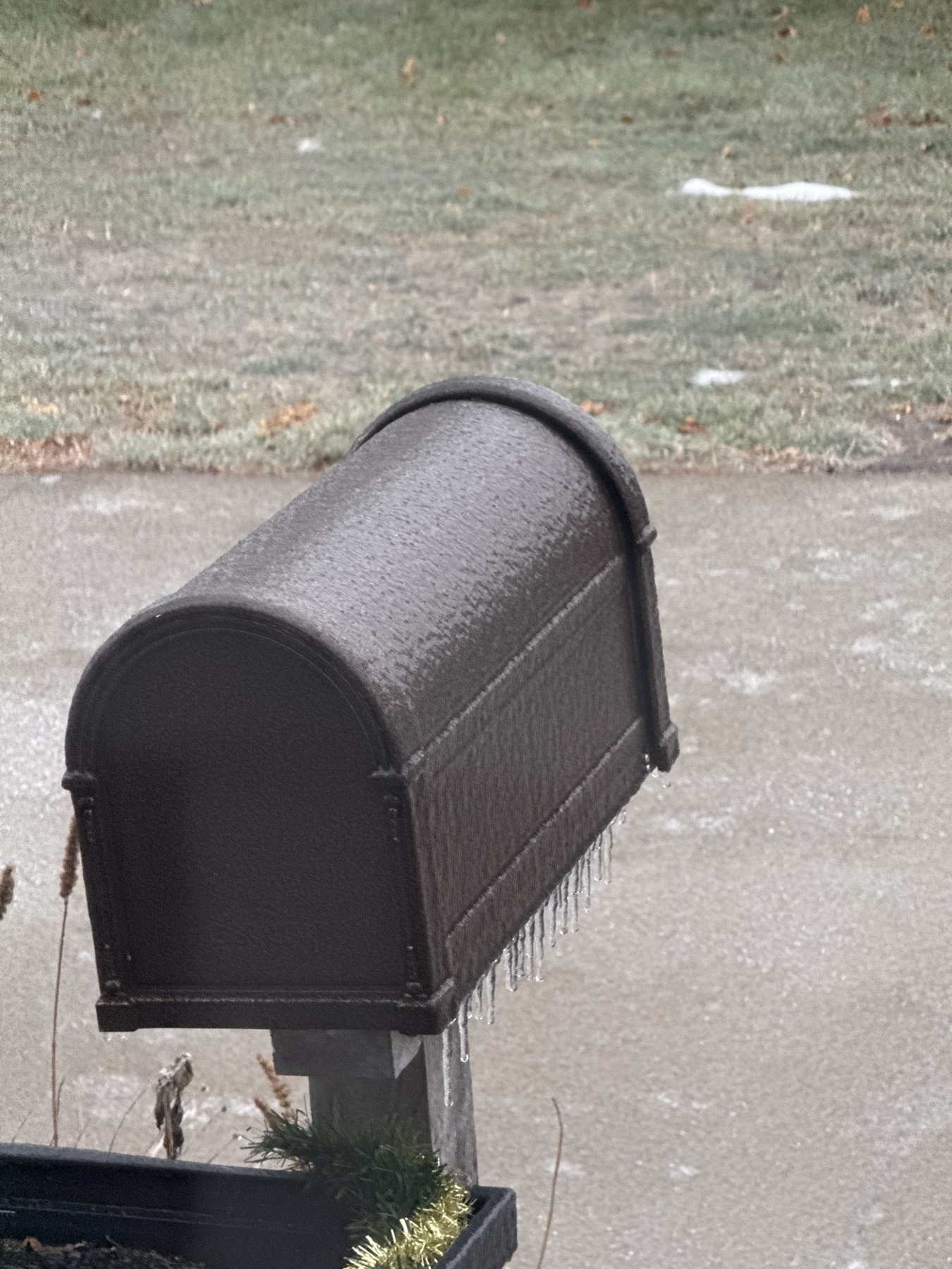 A brown mailbox covered in a thin layer of ice